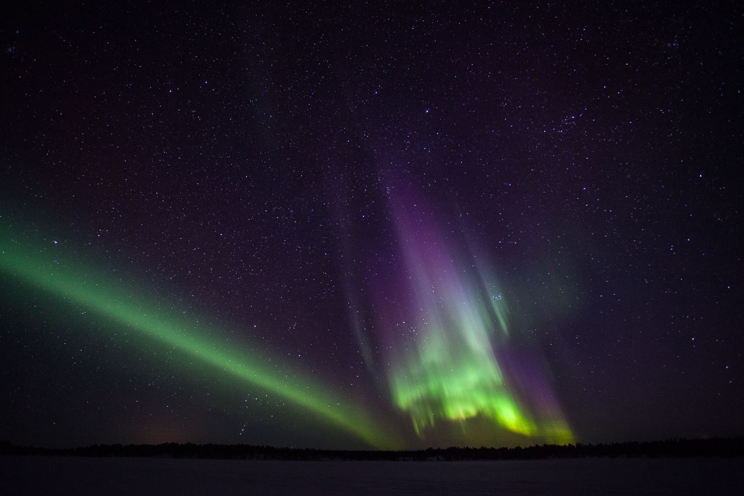 photo d'aurores boréales violettes et vertes sur un lac gelé en suède, près de al frontière avec la Norvège.