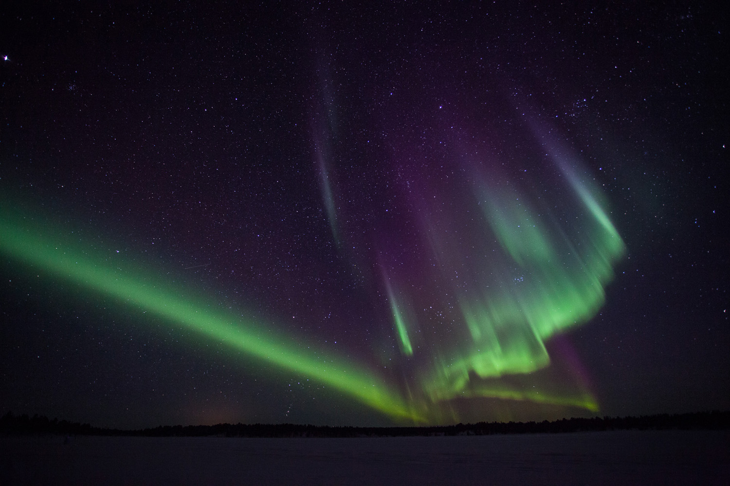 photo d'aurores boréales en drapées, sur un lac gelée en Suède, près de la frontière avec la Norvège.